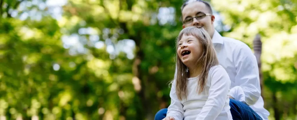 Criança sorrindo em um parque perto do pai Criança sorrindo em um parque perto do pai
