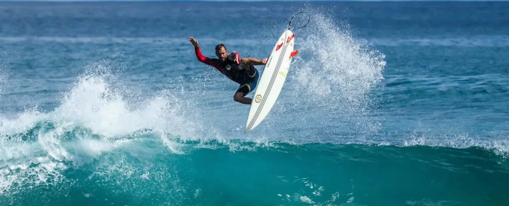 Homem surfando em mar de águas claras Homem surfando em mar de águas claras