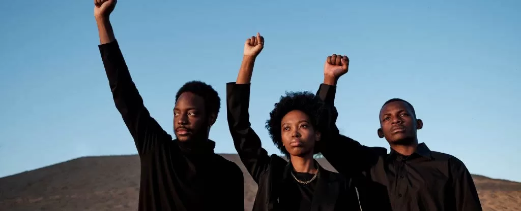 Pessoas negras fazendo símbolo de resistência com as mãos