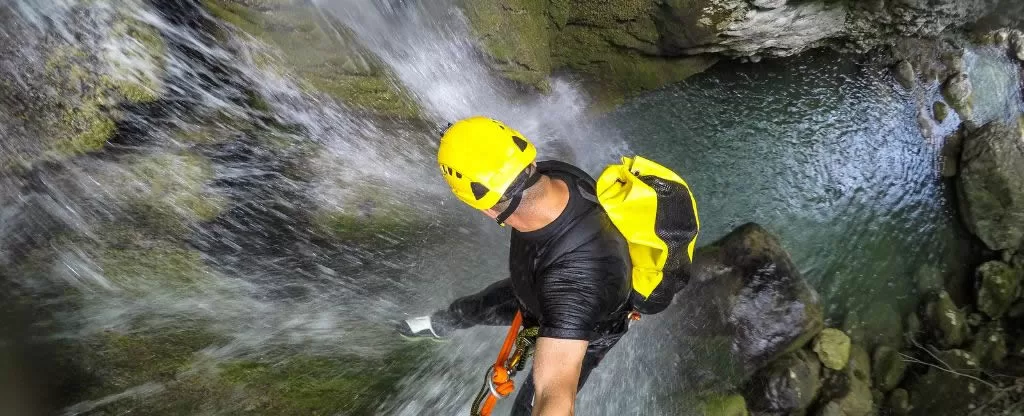 Homem realizando rapel em uma cachoeira Homem realizando rapel em uma cachoeira