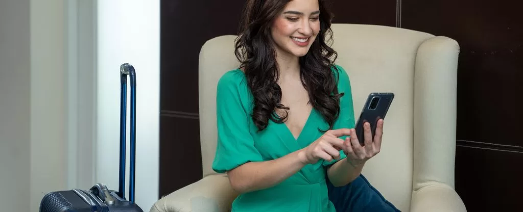 Mulher olhando para celular - Salas vips na Rodoviária Novo Rio