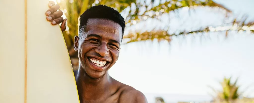 Homem sorrindo com prancha de surf Homem sorrindo com prancha de surf
