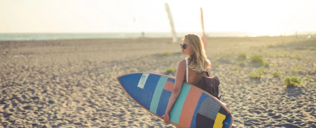 Mulher segurando prancha de surf na areia - Trip surf